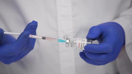 Arzt erstellt Covid19-Impfstoff aus der Phialflasche und Füllspritze zur Impfung