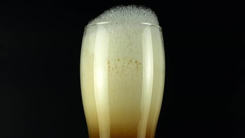 Refreshing Beer Pouring into a Glass on Black