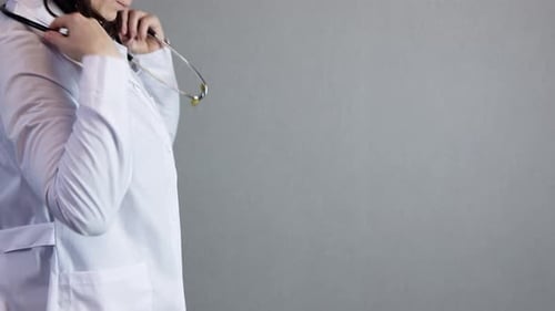 Doctor Putting On Stethoscope In Front of Gray Background