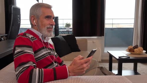 Senior Man Relaxing with Mobile Phone at Home