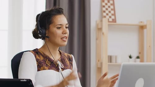 Woman with Headset Works on Laptop at Home