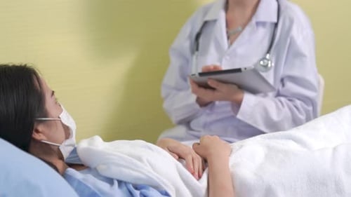 Doctor Wearing Face Mask Proficiently Talks with Patient at Hospital Ward