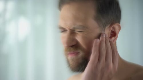 Mann fühlt Schmerzen im Mittelohr, Meningitis und Hörverlust, Entzündung, Nahaufnahme