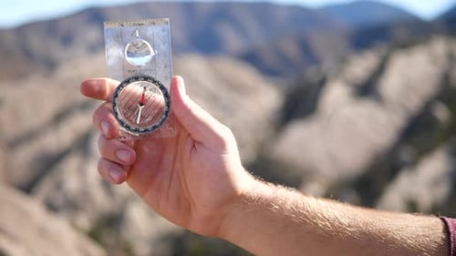 A man holding a survival compass to find his location and the direction he is searching for in life.