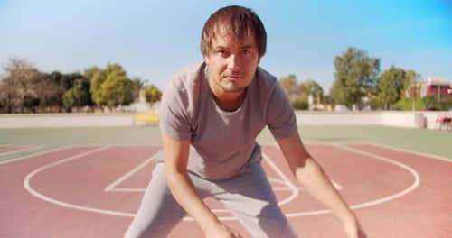 Junger Basketballspieler in Sportuniform trainiert mit einem Ball und Blick in die Kamera