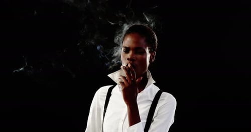 Androgynous man smoking cigar against black background