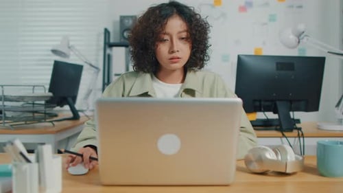 Asiatische indische Geschäftsfrau arbeitet am Laptop und sitzt an ihrem Schreibtisch in einem kreativen Büro
