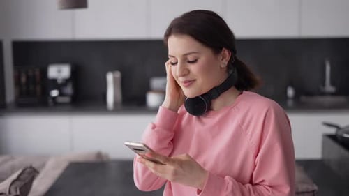 Woman Listening to Music with Headphones in Kitchen