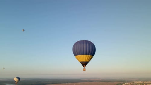 Drohnen-Luftaufnahme eines bunten Heißluftballons mit ukrainischer Flagge, die über den grünen Park in kleinem Raum fliegt