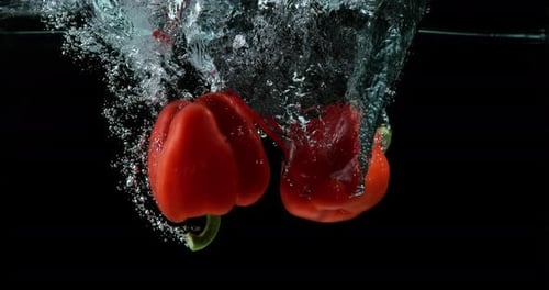Red Bell Peppers Splashing Into Water Tank