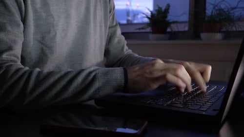 Adult Typing on Laptop at Night