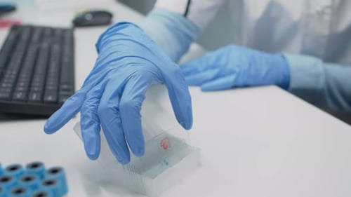 Focused Scientist Examining Microscopic Slide in Lab