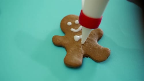 Hand of Human is Decorating By White Glaze Gingerbread Biscuit