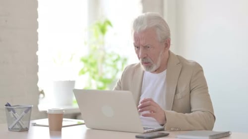 Senior Man Using Laptop Appears Frustrated