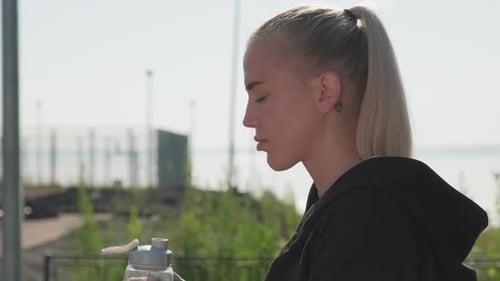 Female Athlete Drinking Water At Outdoor Training