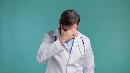Bearded Doctor Covering Face with Hand