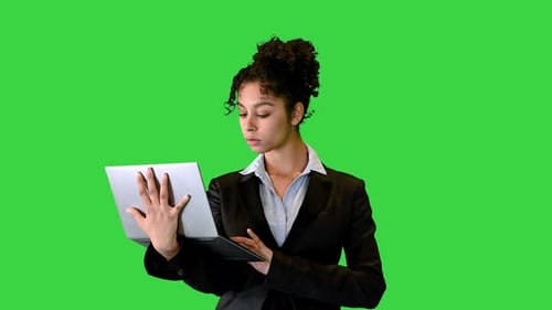 Young African Woman Formally Dressed Standing Working on Laptop Computer on a Green Screen, Chroma