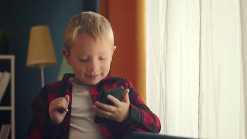 Young Boy Using Mobile Phone Indoors by Window
