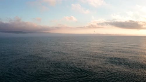 Low clouds over a sea coastline at sunrise