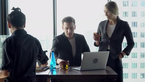 Empresária e empresário se reunindo com um laptop que parece e discutindo juntos.