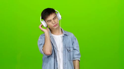 Guy Listens To the Music in the Headphones and Adjusts To the Positive. Green Screen