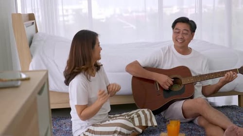 Happy Couple Singing and Playing Guitar at Home