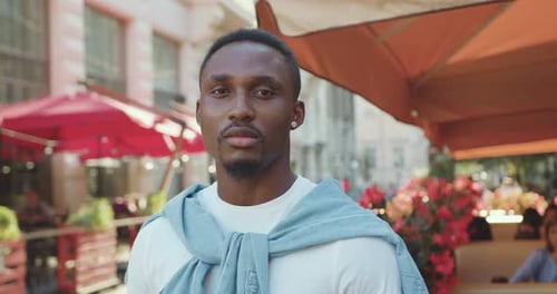 Afro-Américain debout sur le fond d'un café Bright Cozy Street et regardant la caméra