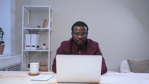 African Man Closes Laptop with Hand and Makes Happy Face in Office Spbas