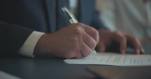 Close up of a businessman's hands signing a contract during a business meeting. Slow motion