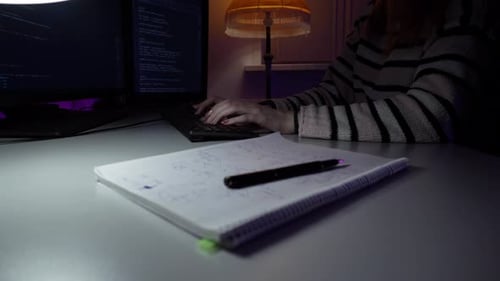 Jovem mulher caucasiana está sentada na frente do computador e codificando novo programa digitando no teclado