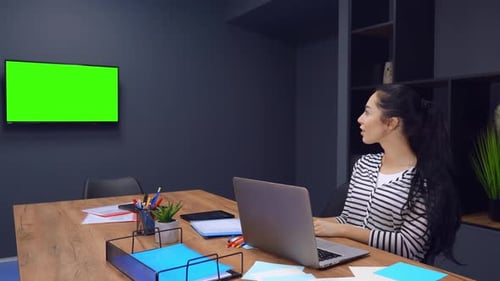 Cheerful Laughing of Working Woman Who Is Looking at TV with Green Screen