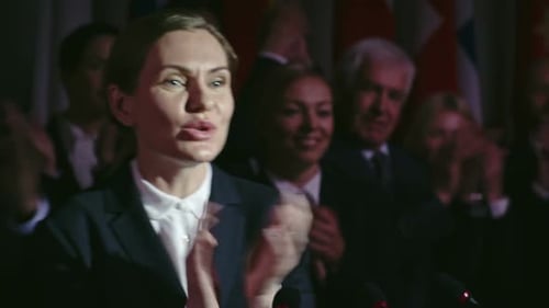 Woman Giving Speech to Audience with Flags