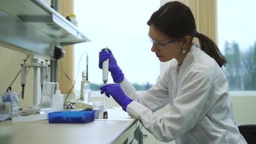 Female Scientist Carefully Pipetting in Laboratory