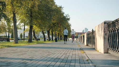 Portrait of Girl and Guy Jogging Together in Modern City Enjoying Sports on Summer Day