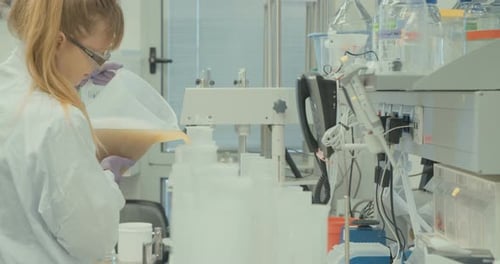 Scientist Pouring Liquid into Containers in Lab