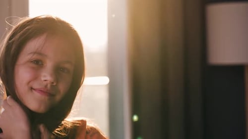 Portrait of a Brunette Girl Smiling and Playing with Her Hair in the Rays of the Setting Sun