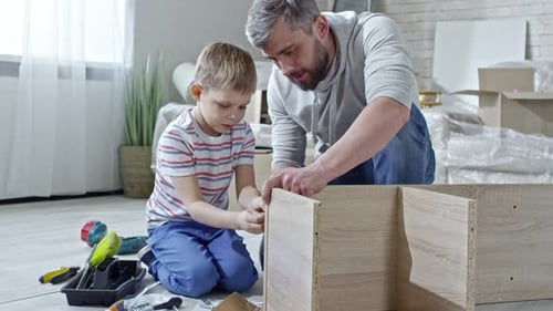 Father and Son Assembling Furniture Together at Home