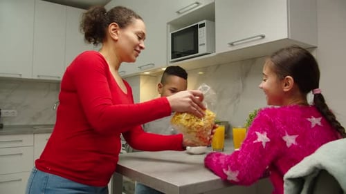 Mother Serving Breakfast Cereal to Children in Kitchen