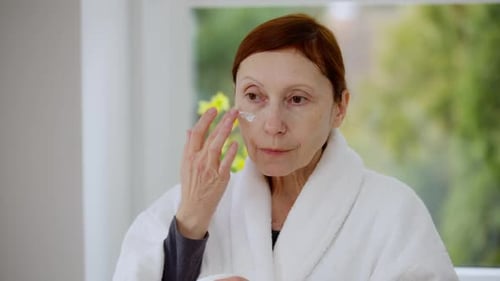 Woman Applying Face Cream in a Bright Interior