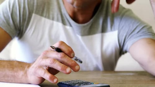 Tense man using calculator in living room