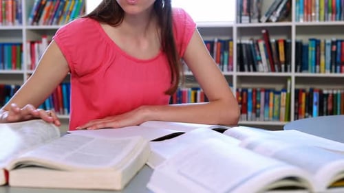 Attentive schoolgirl doing homework in library