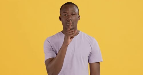 Man Asks for Silence on Yellow Background