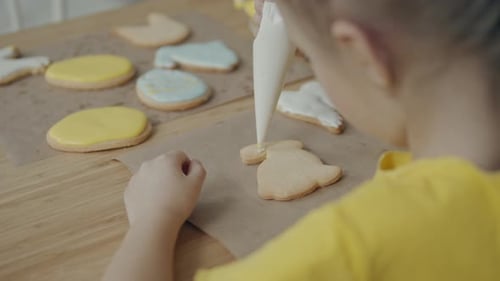 Child Decorating Easter Cookies with White Icing