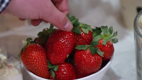The Man Takes a Hand Fresh Juicy Large Strawberry From a Bowl Closeup Outdoors at the Cottage
