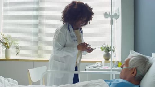 Black Female Doctor Visiting Eldelry Patient in Hospital Ward