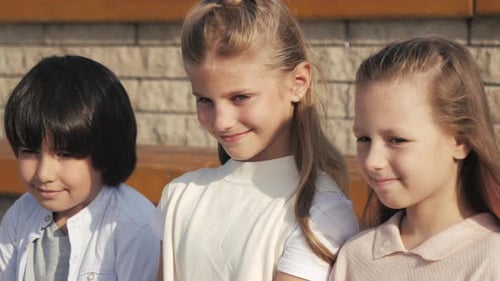Smiling Children Sitting Together in Sunlight
