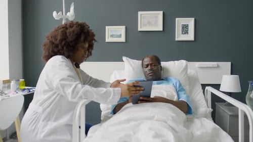 Doctor and Patient Using Tablet and Talking in Hospital Ward