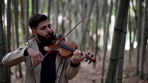 Charismatic Fiddler is Playing Melody in Forest Man is Standing Between Bamboo and Rehearsing