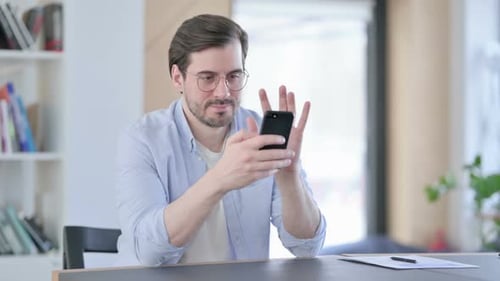 Man in Glasses Celebrating Success on Smartphone in Office