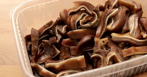 Close-up of Cooked Pig Ear Slices in Container